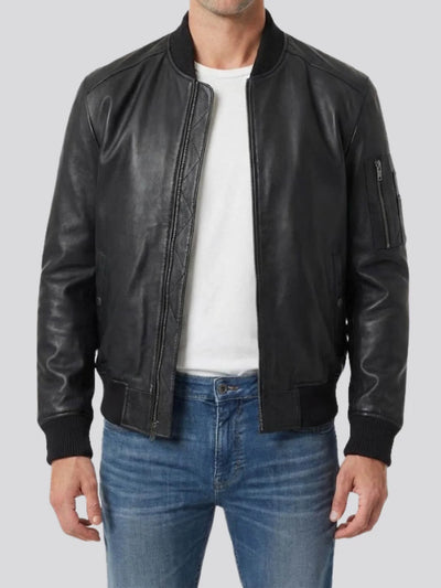 Person wearing a black leather jacket over a white shirt and blue jeans on a light gray background